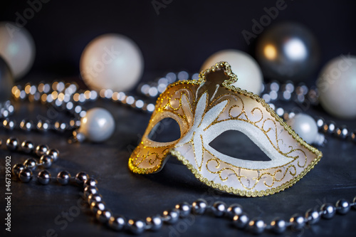 Christmas composition with carnival mask and Christmas tree beads. New Year's horizontal photo in black and white. Christmas concept. Christmas tree decorations in stylish colors.