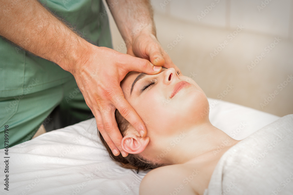 Pretty young caucasian woman receiving a head massage by a male massage therapist in a beauty salon Pretty young caucasian woman receiving a head massage by a male massage therapist in a beauty salon