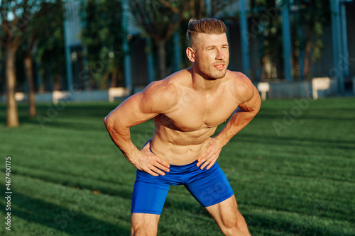 man with muscular body exercising in summer park