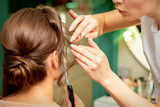 Close Up hairdresser stylist makes hairstyle for a young woman in a beauty salon