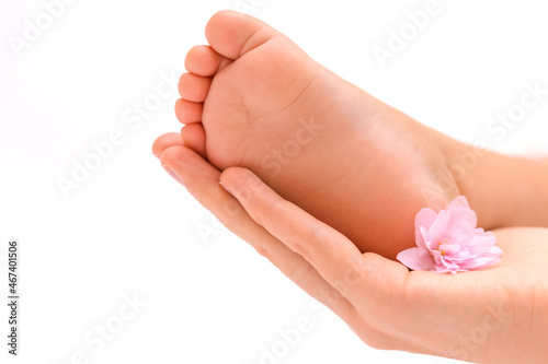The mother's hand holds in the palm of her hand the leg of a newborn baby with a violet flower