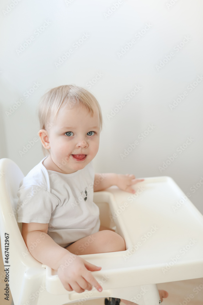 portrait of a funny little baby girl sitting in a high chair 