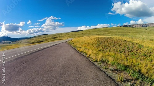 Time Lapse Lockdown Scenic Shot Of Vehicles Moving On Road By Green Landscape Against Cloudy Sky - Creede, Colorado photo