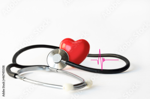 Mock up of a human heart with a phonendoscope and a fragment of a cardiogram on a white background close-up. Conceptual image for cardiology medical examinations or heart disease examinations.