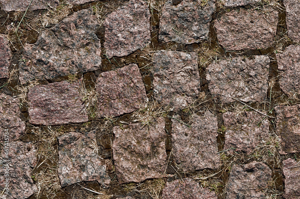 A fragment of a stone-paved road. The background texture of the stone road surface. Pattern.
