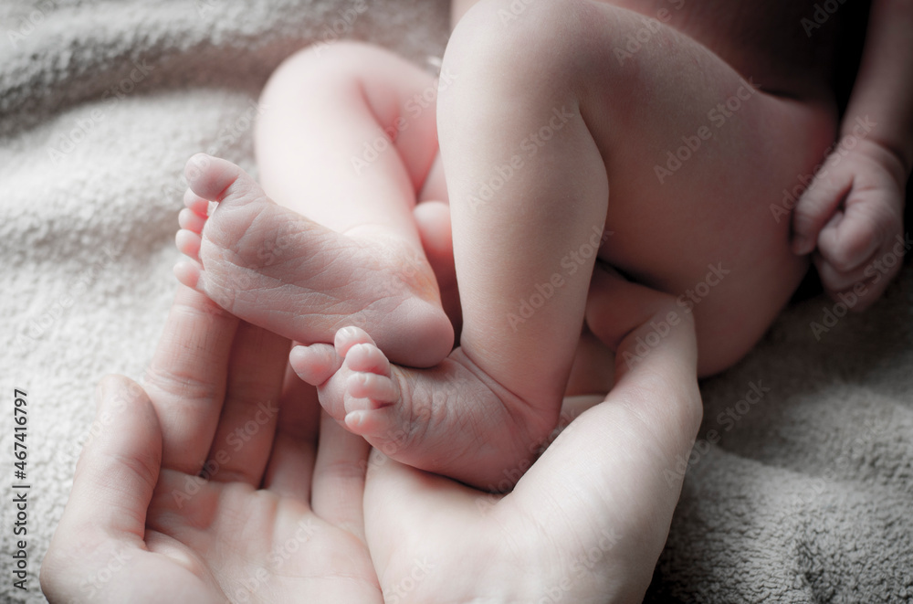 legs of a sleeping newborn in mom's arms