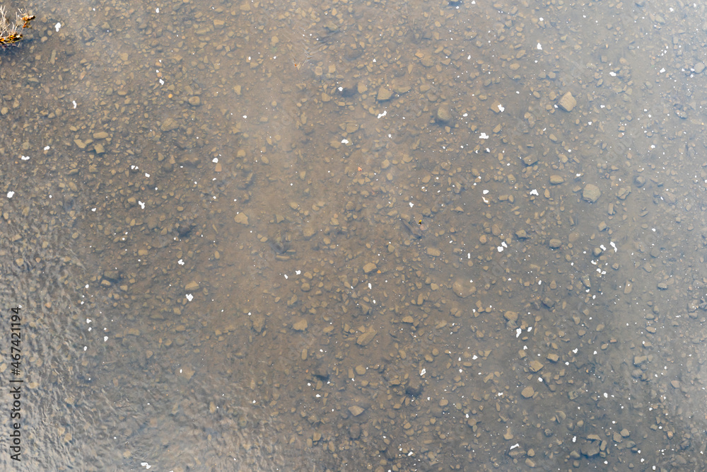 Top down view into the elbe river with water, dirt and small stones. Looking through the clear water to the ground. Brown soil is visible. This can be an abstract background. Top down view into the elbe river with water, dirt and small stones. Looking through the clear water to the ground. Brown soil is visible. This can be an abstract background.