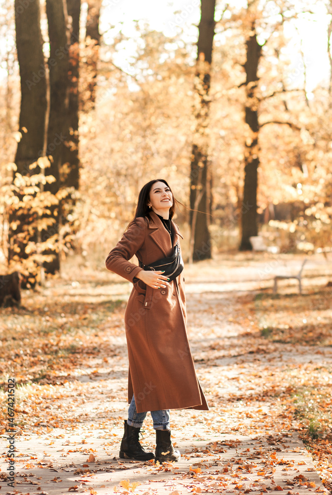 A young brunette woman in a coat in autumn walks in the park A young brunette woman in a coat in autumn walks in the park