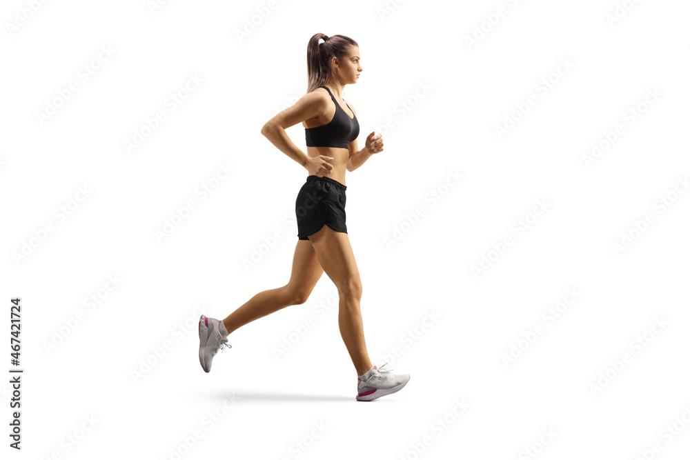 Full length profile shot of a female athlete wearing crop top and shorts and running Full length profile shot of a female athlete wearing crop top and shorts and running
