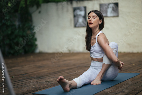 stretching and training, strong, flexible and beautiful woman in white clothes doing yoga pose in the park