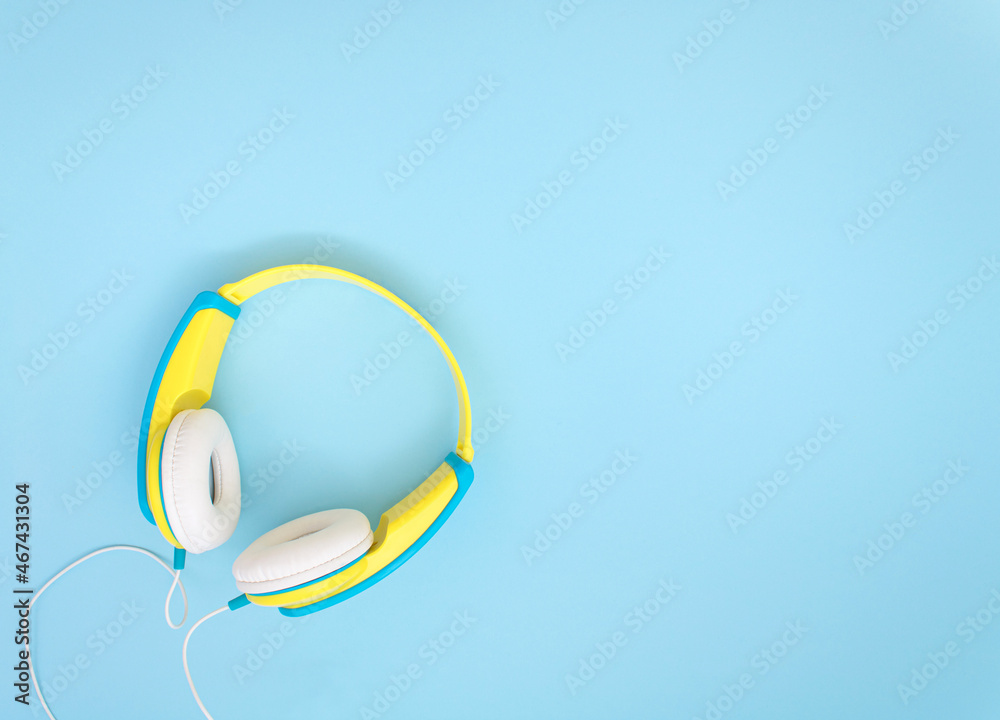 Headphones in cheerful yellow color on blue background. Headphones in cheerful yellow color on blue background.