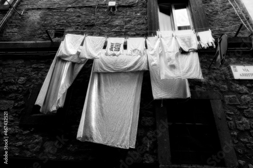 Bottom view of an ancient house in the town of Vitorchiano in Lazio (Italy), white clothes hanging out to dry, black and white photo.