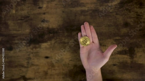 Top view unrecognizable cropped male hand tossing a golden bitcoin coin.