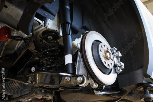 A modern car in a car service on a lift with a removed wheel. Elements of the brake system and suspension. Selected focus.