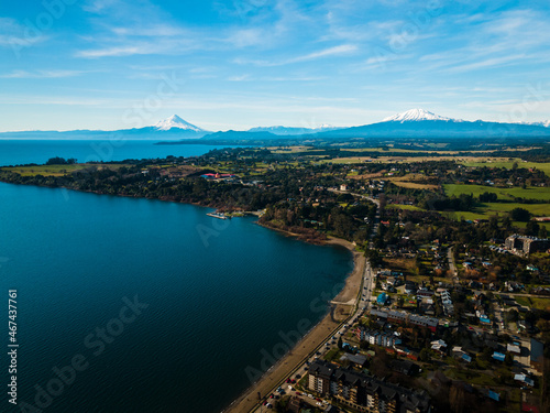 Aerial view of the city of Puerto Varas with the osorno and calbuco volcanoes in the background on a sunny day.