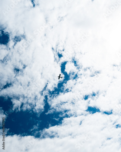 Nadir view of a passing airplane against a cloud-filled background