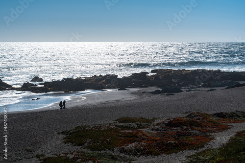 Couple enjoying a walk on the shore of pichilemu's infiernillo beach on a sunny day.