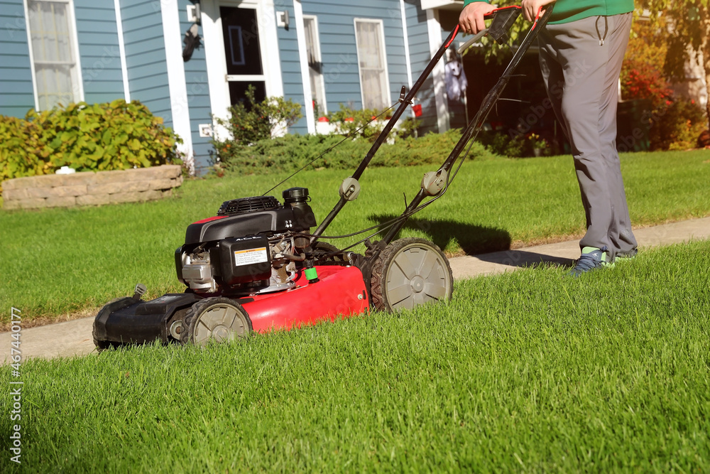 Mowing the grass with a lawn mower in sunny autumn. Gardener cuts the lawn in the garden. Mowing the grass with a lawn mower in sunny autumn. Gardener cuts the lawn in the garden.
