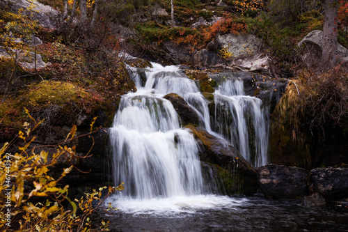 Beautiful Kullaoja waterfall flowing in the middle of autumn colors. Shot near Salla, Northern Finland. 