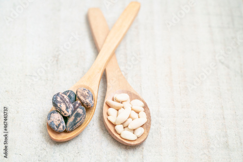 shelled and whole pine nuts in spoon on the wooden background with copy space