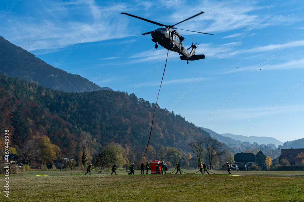 Firefighters fill a water Bucket of an Austrian Armed Forces S-70