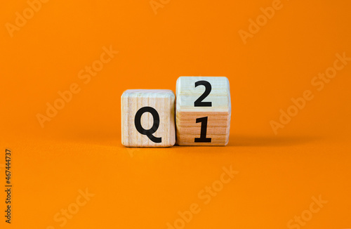 From 1st to 2nd quarter symbol. Turned a wooden cube and changed words 'Q1' to 'Q2'. Beautiful orange table, orange background. Business, happy 2nd quarter Q2 concept, copy space.