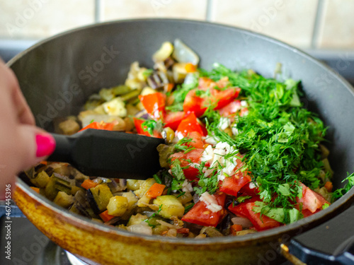 Cubes of fresh vegetables are fried in pan. Studio Photo