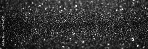 Black glitter lights. Shiny sparkles, bokeh effects, glowing surface. Selective focus, christmas abstract panoramic banner, background