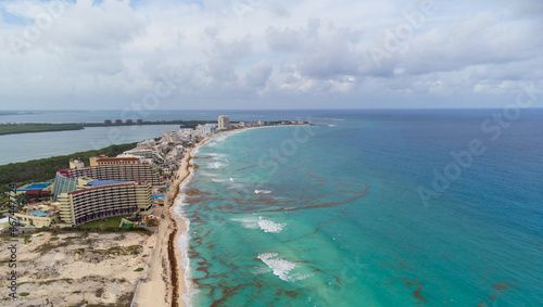 Aerial view. Resort town, sandy beaches, tall houses, hotels. The turquoise water near the shore is polluted with algae. Cloudy sky. Climate change, global warming. Poisoning with wildlife toxins.
