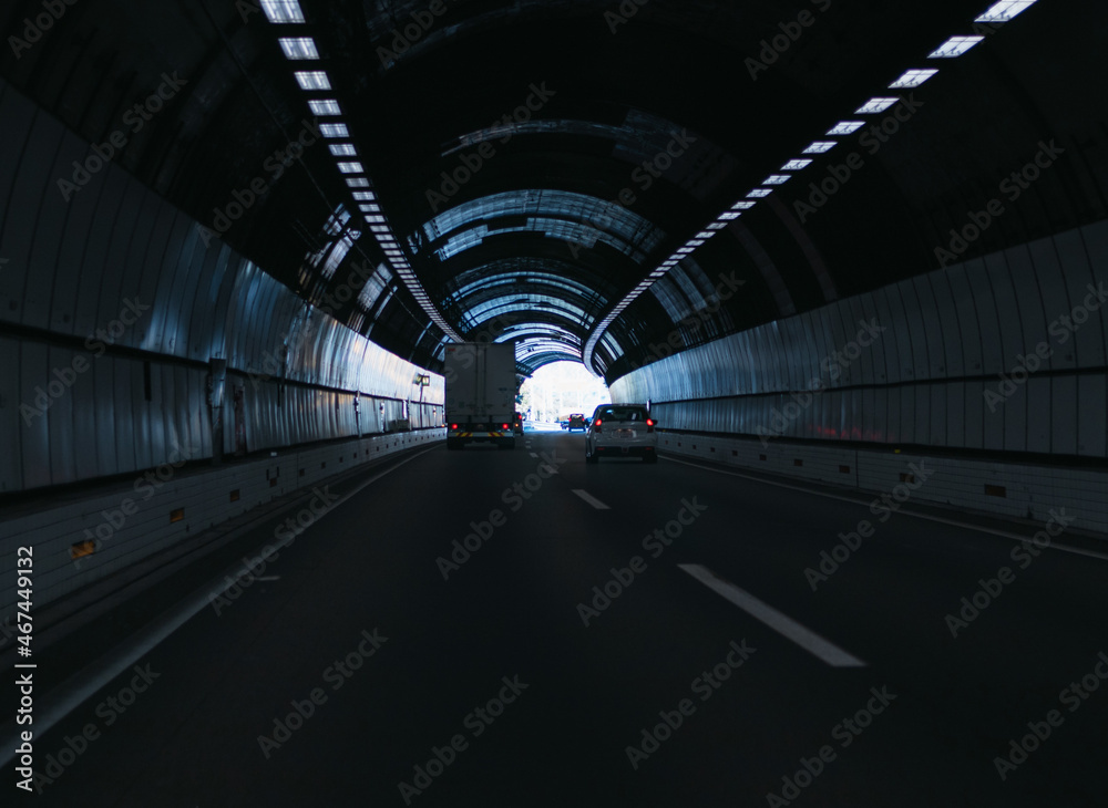 A truck and cars driving through a tunnel near the end of it