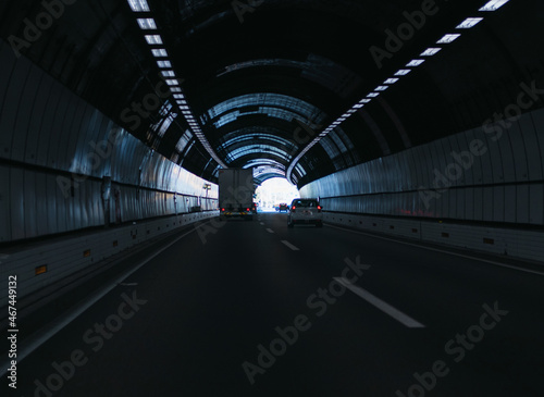 A truck and cars driving through a tunnel near the end of it