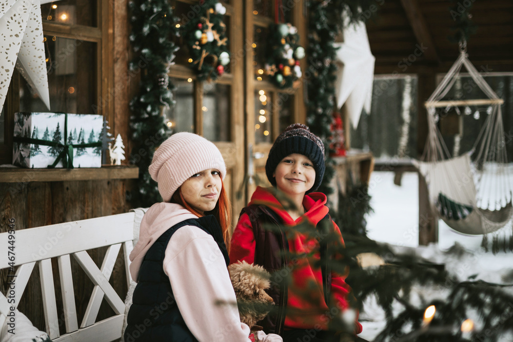 two children boy and teenage girl with poodle dog sitting on porch of village house and having fun during Christmas winter holidays, Christmas and New year vacation concept