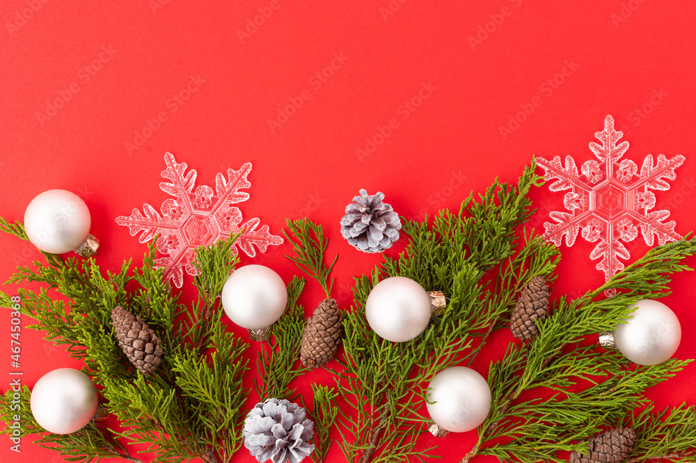 Stylish New Year and Christmas composition on a red background. Openwork white snowflakes, coniferous branches, cones, Christmas balls. Beautiful frame for your inscription. New Year Christmas.