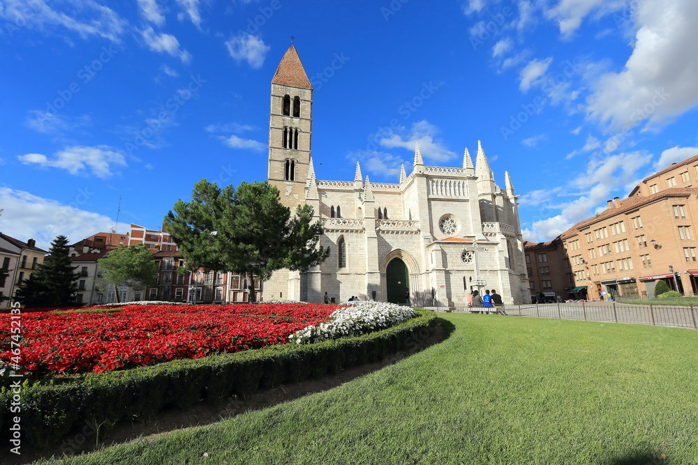 spring day in front of the church of Nuestra Señora la Antigua in Valladolid. Flowery flower beds and blue sky with white clouds.