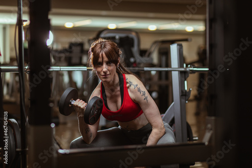Fit young woman lifting heavy weights alone