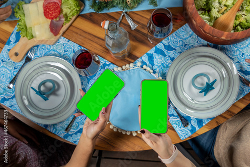 hands holding a cell phone with green screen, with a christmas table in the background
