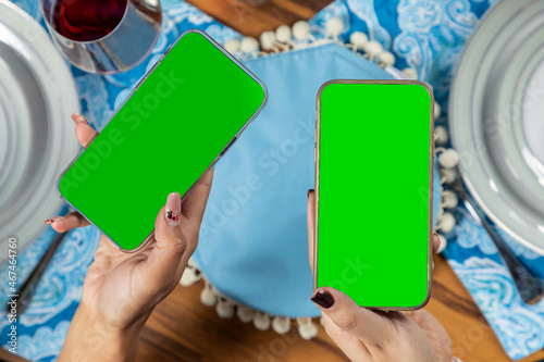 hands holding a cell phone with green screen, with a christmas table in the background