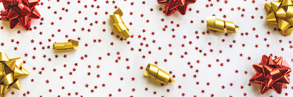Banner is made on a white background with small red stars, gold and red bows and gold ribbons, for holiday promotions, top view, close-up Banner is made on a white background with small red stars, gold and red bows and gold ribbons, for holiday promotions, top view, close-up