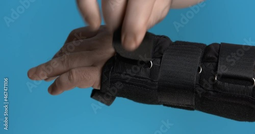 The person takes off the wrist orthosis by unfastening all the straps on it. Close-up. photo