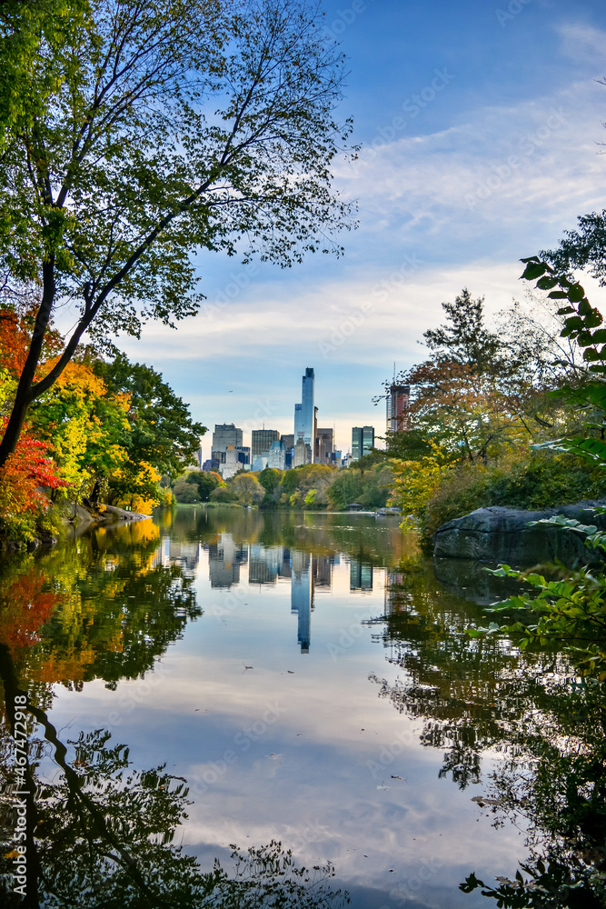 Central Park lake with skyline reflection in the background, during fall season.