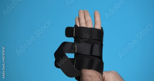 A man puts on a wrist orthosis and fastens the belts. Close-up.