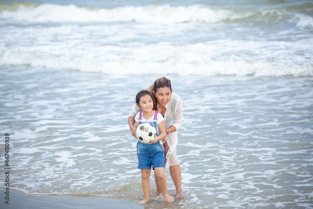 Happy mom and daughter Having Fun Playing Soccer on the Beach. Happy family having fun running on beach. Relaxing holiday concept. Travel attention Happy mom and daughter Having Fun Playing Soccer on the Beach. Happy family having fun running on beach. Relaxing holiday concept. Travel attention