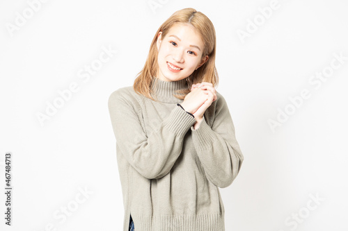 手を組んでお願いするセーターを着た女性