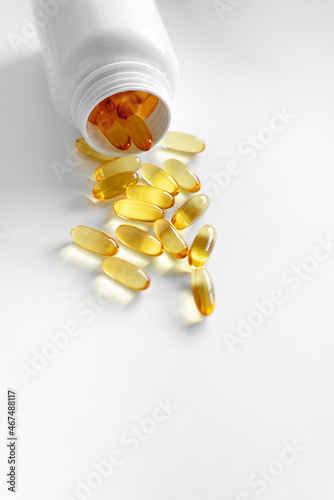 Oliecapsules (zachte capsules) of voedingssupplementen: visolie, omega-3, omega-6, omega-9, vitamine A, vitamine D3, vitamine E, teunisbloemolie, bernagiezaadolie. Gele zachte capsules op een witte ac photo