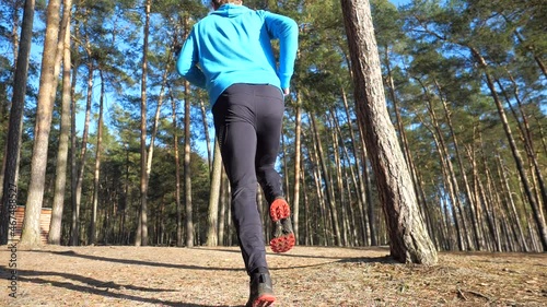 Athlete in a blue hoodie runs along the shore. Evening run in nature.