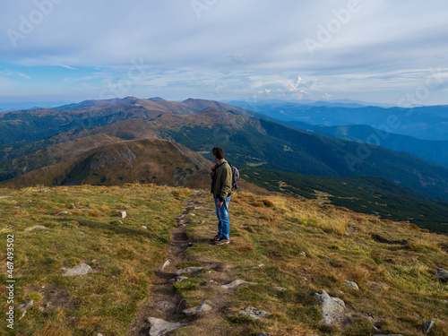 Man standing on top of the mountain relaxing and enjoying beautiful summer landscape. A panoramic view of the Carpathian Mountains from Hoverla in Ukraine. Hiking adventure lifestyle extreme vacations