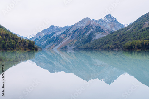 Beautiful blue Kucherla lake. Reflection of mountains in the water. Summer vacation in the mountains. Arrow image formed by reflection in the water. Russia, Altai Mountains.