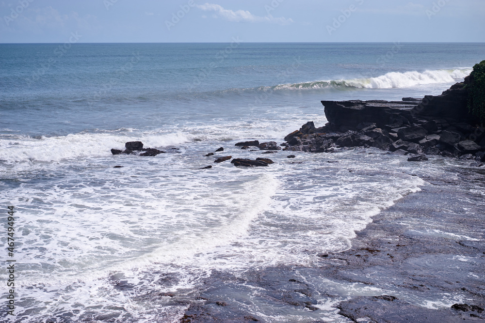 Beautiful landscape with ocean waves and black rock.