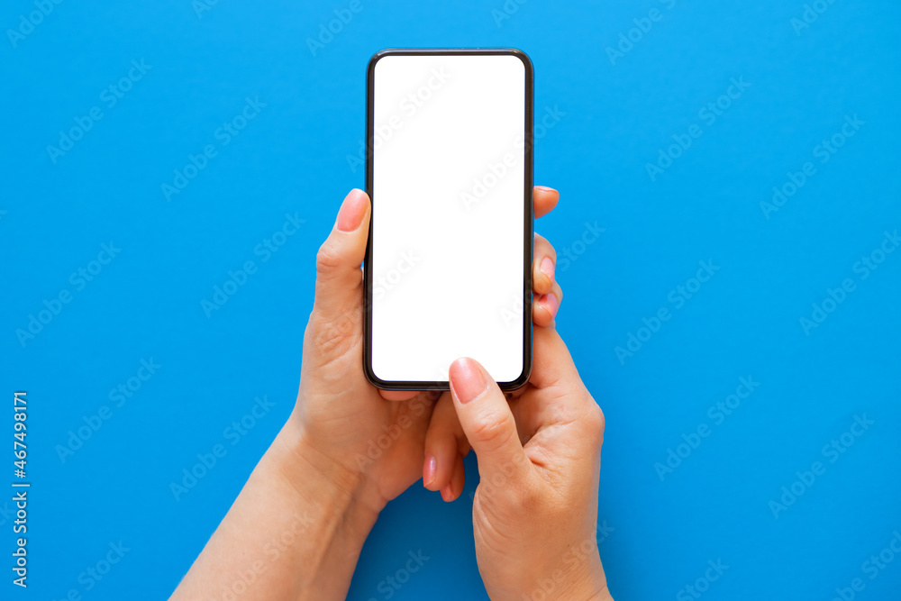 Mobile phone with blank white screen held in both hands on blue background