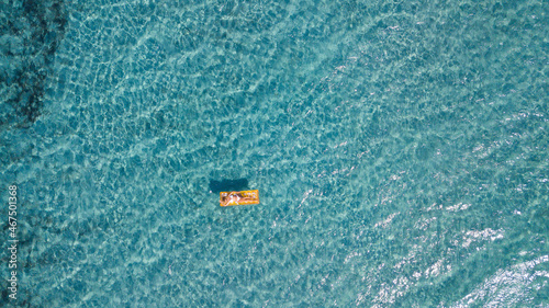Valokuva Female tourist enjoy floating on transparent blue sea water laying no a colorful inflatable lilo mattress